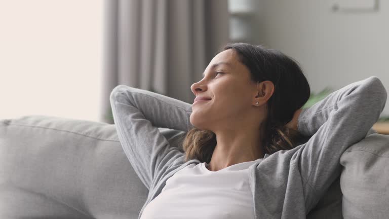 Happy relaxed woman rest lounge on couch enjoy peaceful day