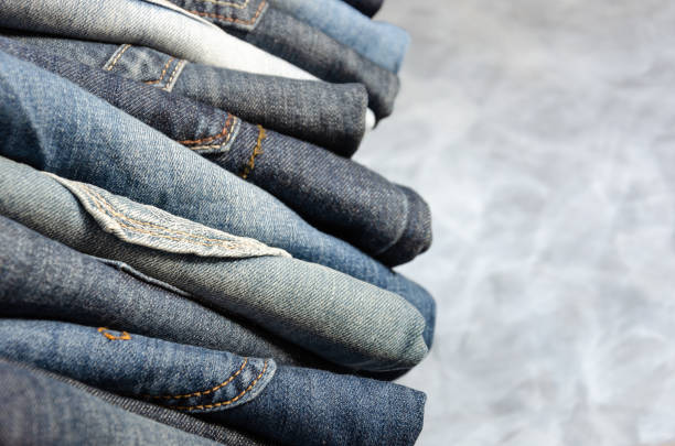 istock A stack of carelessly folded jeans on gray background. Close-up of jeans in different colors. Jeans texture or denim background. Copy space. Selective focus 1177227659