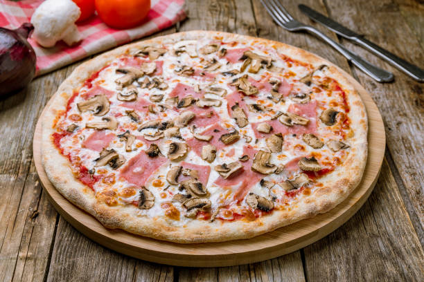 istock Pizza with ham and mushrooms on wooden table 1177227956