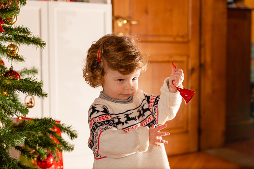 Baby girl decorating Christmas tree in family living room