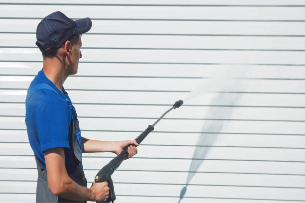 istock Worker in overalls washes a white wall from a siding with a water gun 1177228434