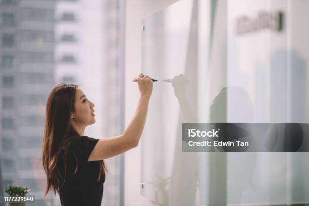 An Asian Chinese Female Writing On White Board With Her Marker Pen During Conference Meeting In Office Conference Room Stock Photo - Download Image Now