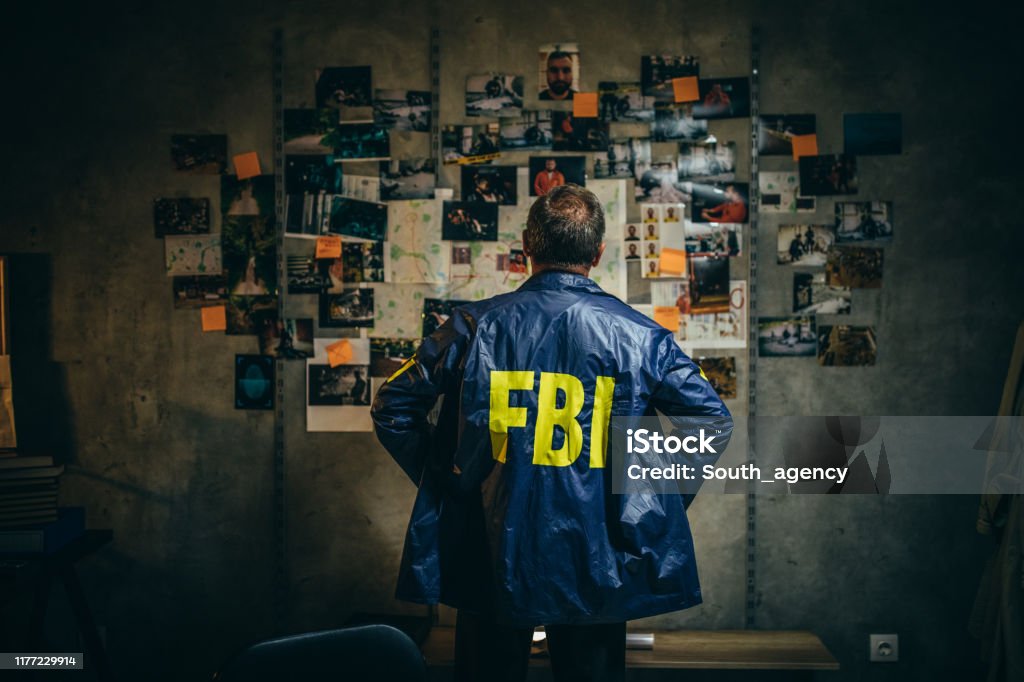 Mature FBI agent works on a case alone One man, mature FBI agent working on a case in dark office. Detective Stock Photo