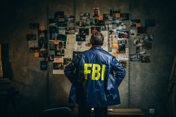 Mature FBI agent works on a case alone One man, mature FBI agent working on a case in dark office. criminal investigation photos stock pictures, royalty-free photos & images