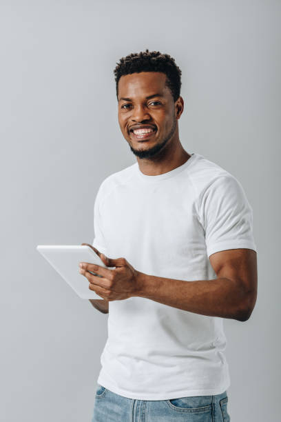 istock happy African American man holding digital tablet and looking at camera isolated on grey 1177233933