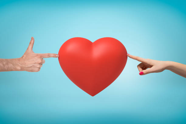 istock Woman's hand on the right and man's hand doing finger gun on the left touching a big red Valentine heart in the middle on blue background. 1177237627