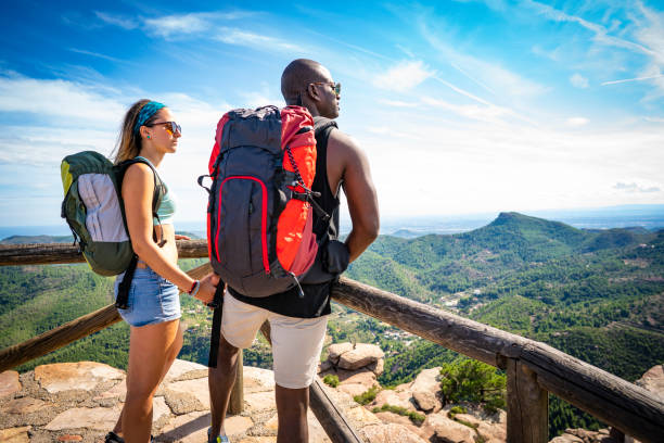istock Couple ethnic trekking looking at mountain peak 1177239850