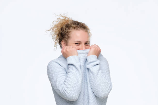 istock young caucasian curly woman hiding face under blue sweater being shy 1177243818