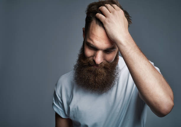 istock Bearded young man standing with a hand in his hair 1177246143
