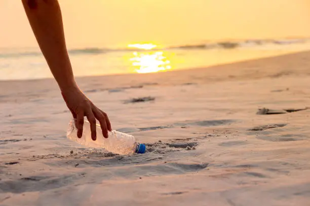Hand woman picking up plastic bottle cleaning on the beach , volunteer concept.