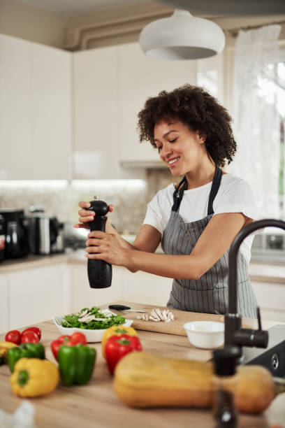 Mixed race woman adding pepper in food. stock photo