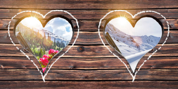Summer and winter mountain view through a heart window on a pasture