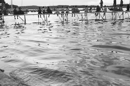 Madison, WI - July 4, 2019. Views of Lake Mendota with the general public enjoying the summer holiday at the University of Wisconsin-Madison Student Union on US Independence Day 2019. The UW-Madison student union is a popular gathering and recreation place for families, college students, and the general public of Madison, WI. Shot on black and white film for vintage look