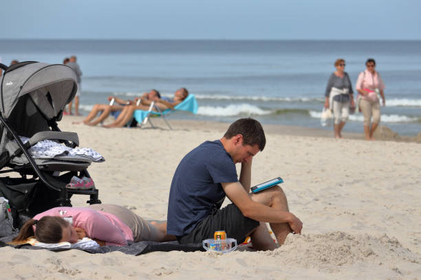 l'homme avec la jeune famille détend sur la plage affichant un e-book - reading beach e reader men photos et images de collection