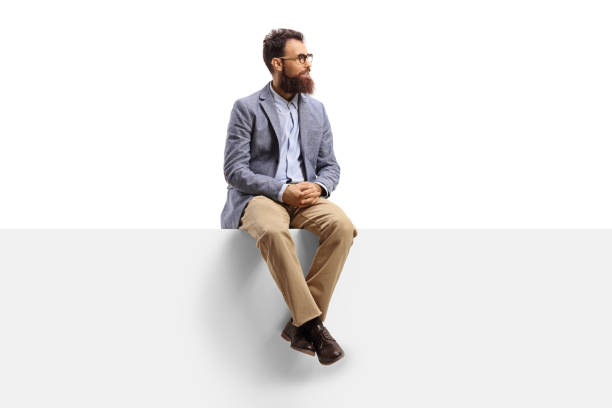 Bearded man sitting on a banner and looking to the side isolated on white background