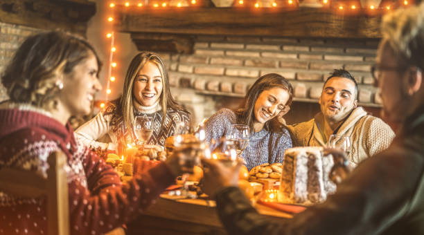 amici felici che assaggiano il cibo dolce natalizio a casa festa divertente - umore di capodanno con toast con bicchieri di vino bianco - concetto di vacanza invernale con i giovani che mangiano insieme - filtro caldo a luci a bulbo - pandoro foto e immagini stock