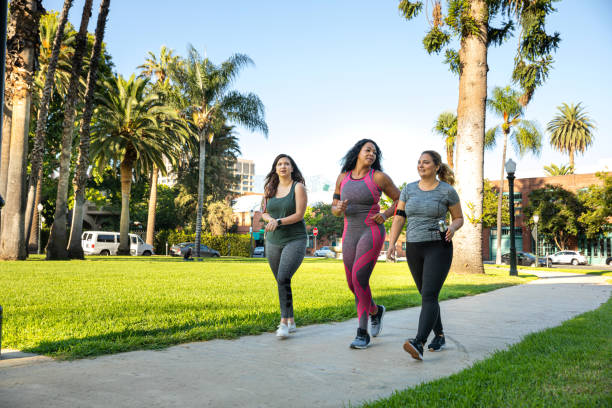 young women jogging and getting healthy at the park - walking exercising relaxation exercise group of people imagens e fotografias de stock