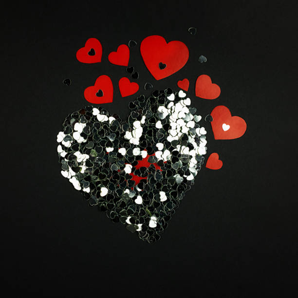 istock Decorative red hearts and silver confetti on a black background. 1177273157
