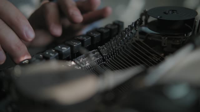 Writer typing on a typewriter, taken from side. Vintage scene