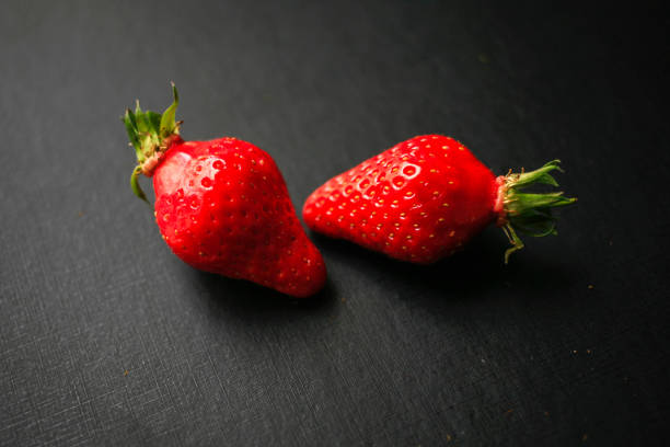 istock Two delicious strawberries on black background 1177275365