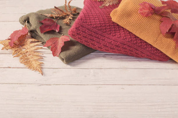 istock stack of sweaters with autumn leaves  on  white wooden table 1177275714