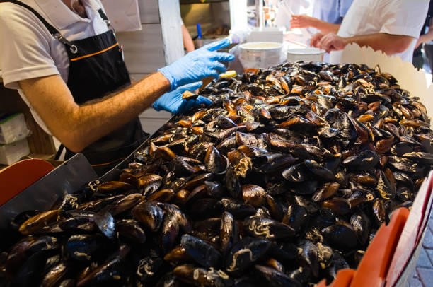 Heap of mussels in shells stuffed with rice and served with lemon. Man selling midye traditional Turkish food in Midyeci Ahmet cafe. Istanbul, Turkey.