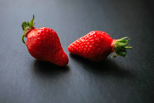 istock Two delicious strawberries on black background 1177279309