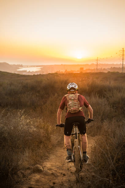 Cycliste de Mountian conduisant dans le coucher du soleil - Photo