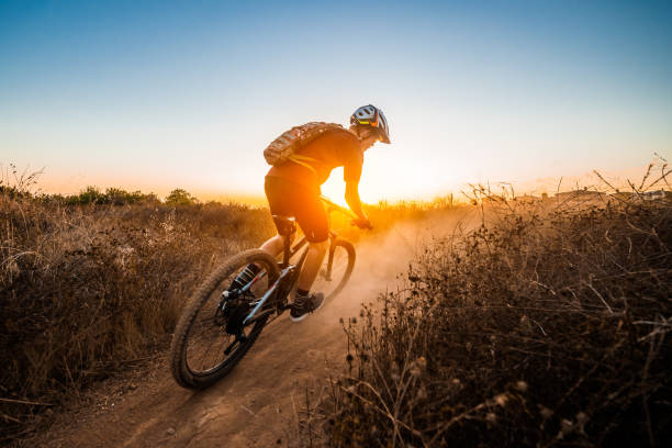 mountian biker riding into the sunset - mountain biking stock-fotos und bilder