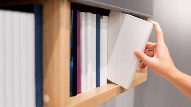 istock Male hand picking white book on bookshelf 1177284980