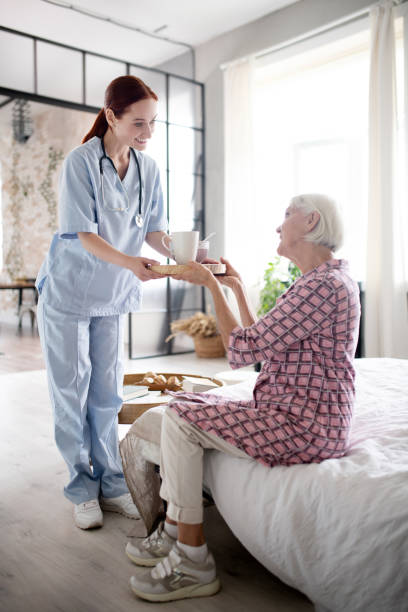 istock Nurse smiling while giving breakfast to aged woman 1177287912