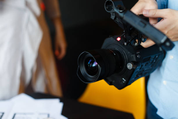 черная кинокамера в руках режиссера крупным планом во время записи - home video camera women videographer digital video camera стоковые фото и изображения