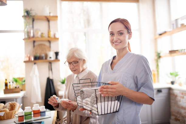Medical attendant standing near pensioner wearing glasses Standing near pensioner. Smiling medical attendant standing near pensioner wearing glasses home caregiver photos stock pictures, royalty-free photos & images