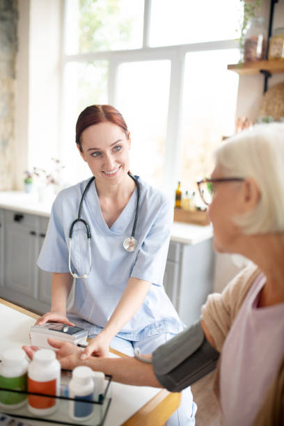istock Caregiver smiling while measuring pressure for aged woman 1177288363