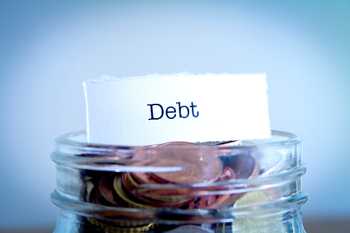 A close-up shot of the word Debt on a jar of coins.