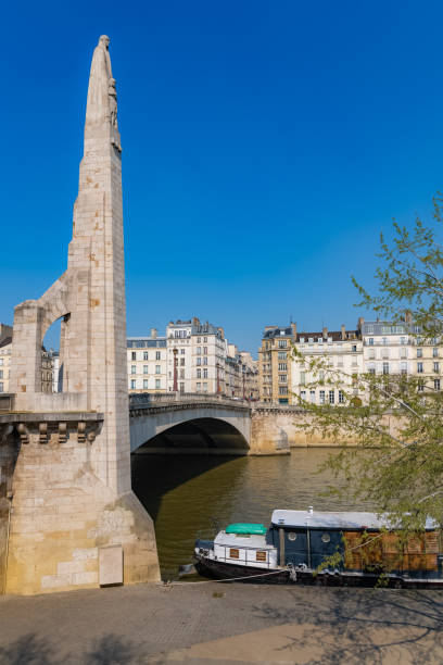 Beautiful view of a metallic bridge over a river in Paris, surrounded by lush greenery and historic architecture, depicting the charm and scenery of the iconic French capital.