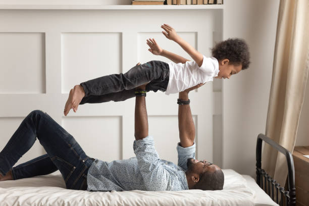 istock Father lying on bed holding son on raised up hands 1177320063
