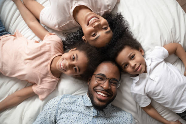 istock Cheerful african family lying on bed smiling looking at camera 1177320072
