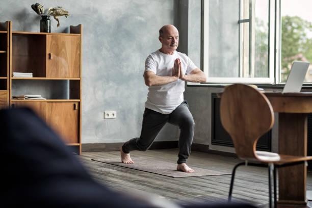 homem latino-americano sênior que está na variação do pose da ioga do guerreiro - stretching yoga men good posture - fotografias e filmes do acervo