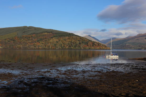 Loch Fyne in Inverary Single boat in Loch Fyne viewed from its shores in Inverary in Autumn loch fyne stock pictures, royalty-free photos & images