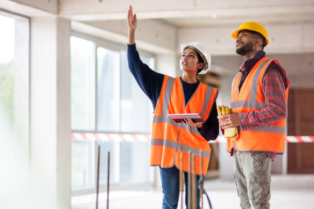 istock Woman holding a tablet and pointing at something while talking to a construction worker at a construction site 1177326281