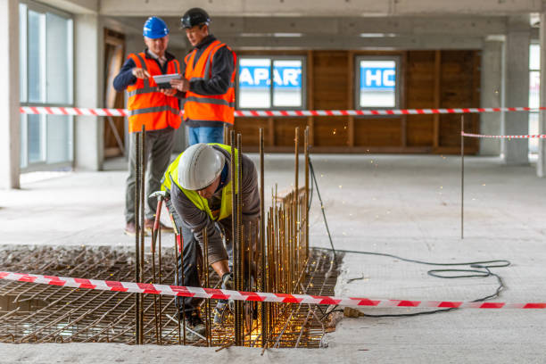 istock Construction worker cutting iron mesh while two men look at a digital tablet in the background 1177326289