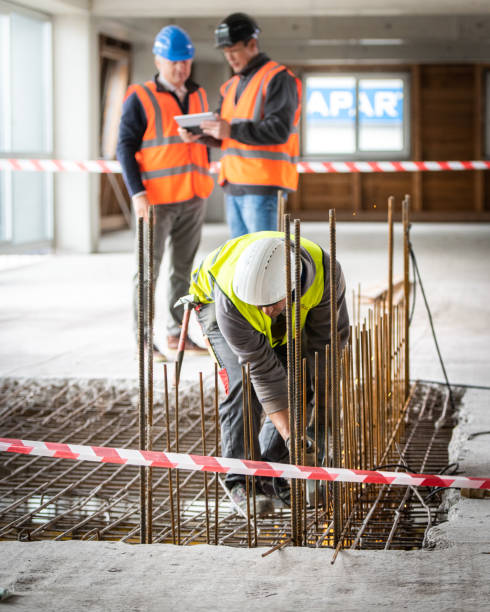 istock Construction worker cutting iron mesh while two men look at a digital tablet in the background 1177326294