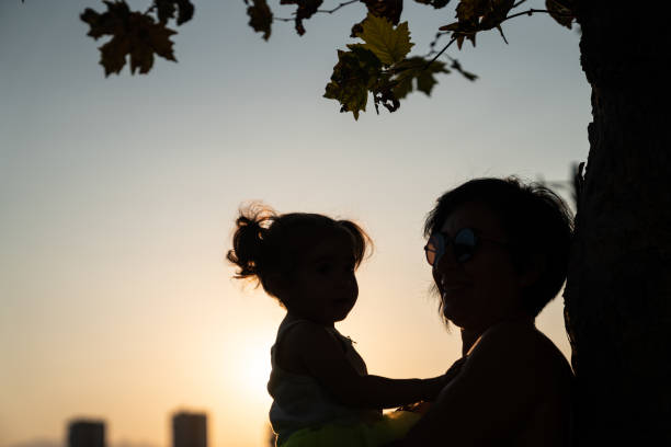 istock Mother Holding Baby Daughter Under Autumn Tree 1177328699
