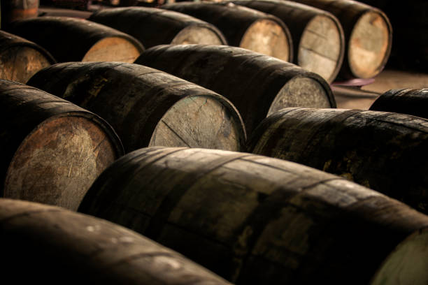 Wooden barrels Old wooden (oak) barrels. Rum or wine aging process. barrel stock pictures, royalty-free photos & images