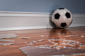 Broken glass from a window pane on the floor with soccer ball