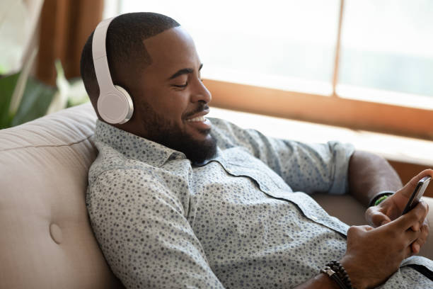 istock Happy african american man lying on sofa at home. 1177334840