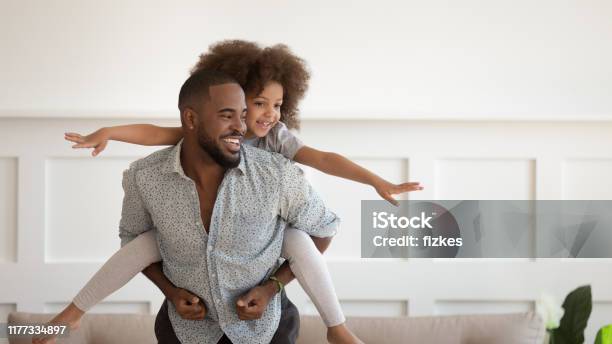 Excited Black Man Giving Piggyback Ride To Happy Cute Daughter Stock Photo - Download Image Now