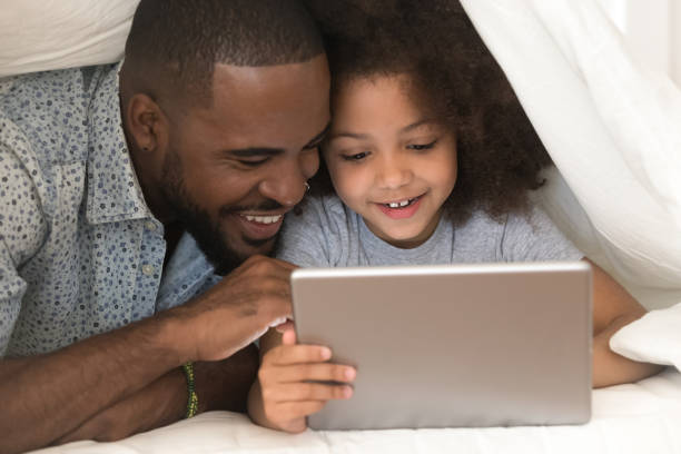 istock Happy african american father using digital tablet with cute daughter. 1177334918