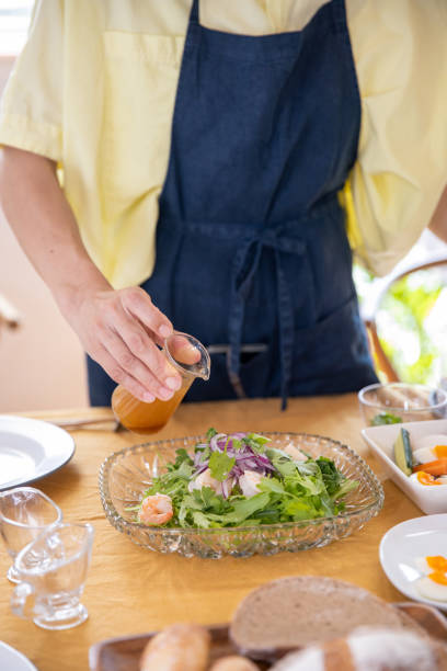 Woman pouring dressing to salad